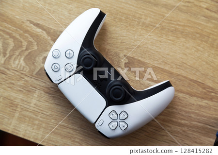 Sony PS5 Wireless Controller, on an oak wooden table, PlayStation is a video gaming brand that consists of five home video game consoles. Istanbul Turkey May 01 2025 128415282