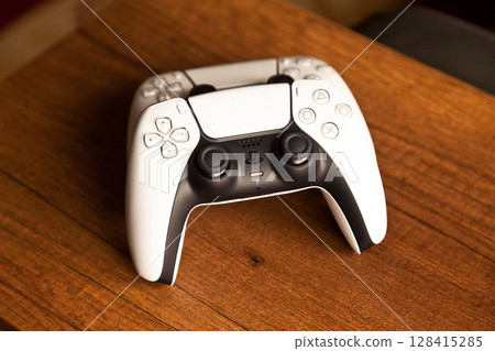 Sony PS5 Wireless Controller, on an oak wooden table, PlayStation is a video gaming brand that consists of five home video game consoles. Istanbul Turkey May 01 2025 Sony PS5 Wireless Controller, on an oak wooden table, PlayStation is a video gaming brand that consists of five home video game consoles. Istanbul Turkey May 01 2025 128415285