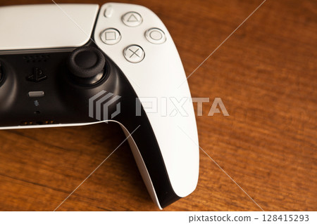 Sony PS5 Wireless Controller, on an oak wooden table, PlayStation is a video gaming brand that consists of five home video game consoles. Istanbul Turkey May 01 2025 Sony PS5 Wireless Controller, on an oak wooden table, PlayStation is a video gaming brand that consists of five home video game consoles. Istanbul Turkey May 01 2025 128415293