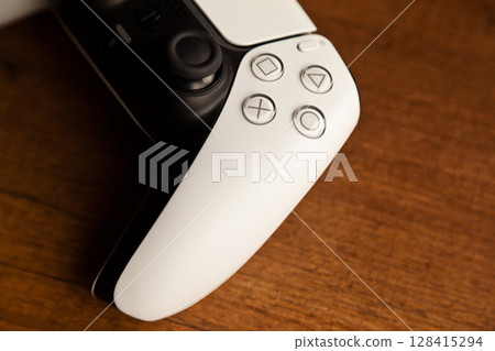 Sony PS5 Wireless Controller, on an oak wooden table, PlayStation is a video gaming brand that consists of five home video game consoles. Istanbul Turkey May 01 2025 Sony PS5 Wireless Controller, on an oak wooden table, PlayStation is a video gaming brand that consists of five home video game consoles. Istanbul Turkey May 01 2025 128415294