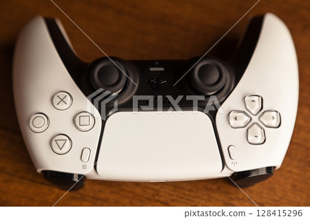 Sony PS5 Wireless Controller, on an oak wooden table, PlayStation is a video gaming brand that consists of five home video game consoles. Istanbul Turkey May 01 2025 128415296