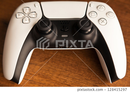 Sony PS5 Wireless Controller, on an oak wooden table, PlayStation is a video gaming brand that consists of five home video game consoles. Istanbul Turkey May 01 2025 128415297