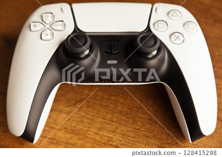 Sony PS5 Wireless Controller, on an oak wooden table, PlayStation is a video gaming brand that consists of five home video game consoles. Istanbul Turkey May 01 2025 128415298