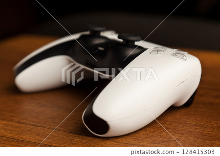 Sony PS5 Wireless Controller, on an oak wooden table, PlayStation is a video gaming brand that consists of five home video game consoles. Istanbul Turkey May 01 2025 128415303