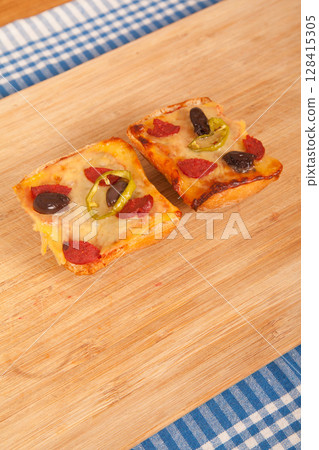 Great looking yummy pizza pieces on blue cloth napkin and wooden bamboo cutting board 128415305
