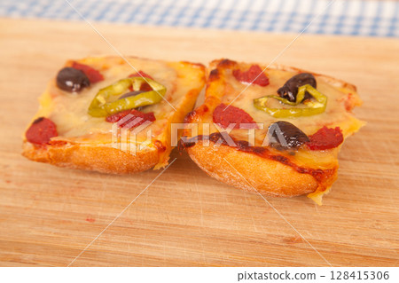 Great looking yummy pizza pieces on blue cloth napkin and wooden bamboo cutting board Great looking yummy pizza pieces on blue cloth napkin and wooden bamboo cutting board 128415306
