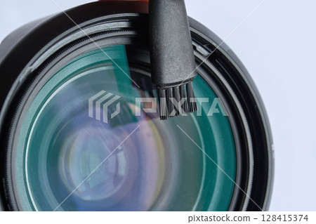 Close up of camera lens with cleaning brush on transparent surface 128415374