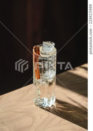 Crystal clear cocktail with ice cubes and cinnamon Crystal clear cocktail with ice cubes and cinnamon 128415999