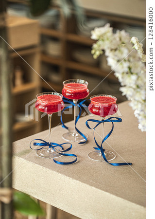 Three red cocktails in glasses with blue ribbons 128416000