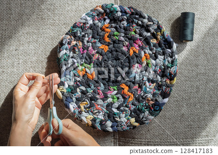Final stitching of round recycled fabric rug 128417183