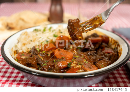 Hearty beef stew with vegetables and rice served on a plate Hearty beef stew with vegetables and rice served on a plate 128417643