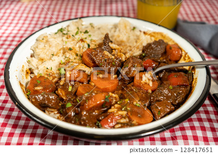 Hearty beef stew with carrots and rice on checkered tablecloth Hearty beef stew with carrots and rice on checkered tablecloth 128417651