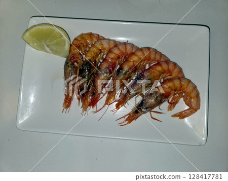 Fresh cooked shrimps with lemon slice on rectangular plate. Mediterranean diet. Spanish tapas Fresh cooked shrimps with lemon slice on rectangular plate. Mediterranean diet. Spanish tapas 128417781