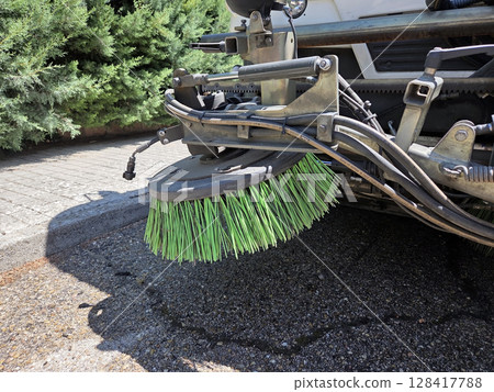 Urban cleanup scene featuring close-up of street sweeper brush in action. A street sweeper or street cleaner Urban cleanup scene featuring close-up of street sweeper brush in action. A street sweeper or street cleaner 128417788