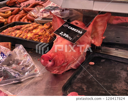 Fresh pork selection in butcher shop featuring pig head display? A pig's head on a market counter in Spain 128417824