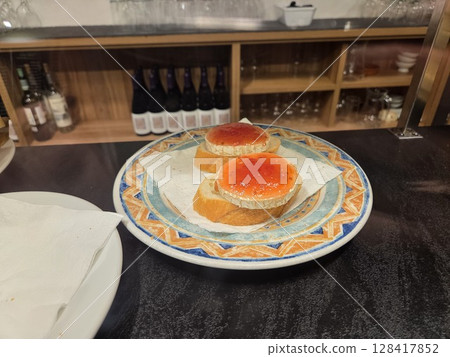 Delicious appetizers with brie cheese and red jam on artisan bread in a rustic setting. World Cheese Day. Close-up. Spanish tapas 128417852