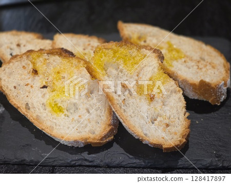 Freshly sliced artisan bread with olive oil on slate surface Freshly sliced artisan bread with olive oil on slate surface 128417897