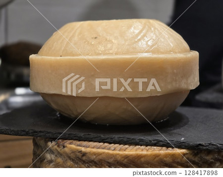 Rustic artisan cheese wheel for culinary and cheese tasting enthusiasts. World Cheese Day. Close-up 128417898