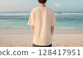 Back view of a young man wearing a beige T-shirt at the beach at dusk | Soft impression 128417951