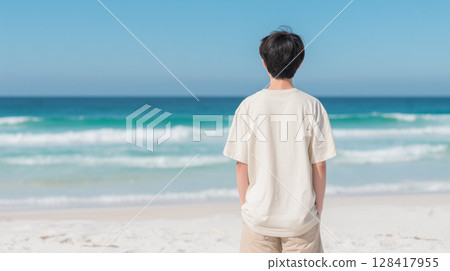 A male student in a T-shirt standing on a white sandy beach with an emerald green sea | Refreshing 128417955