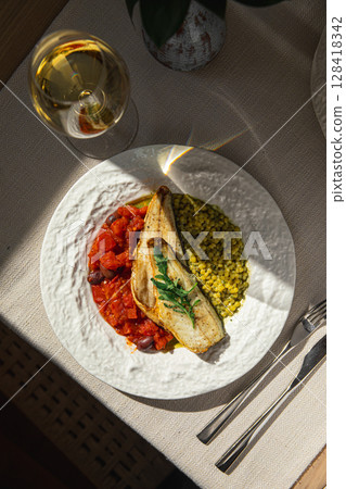 Portion of sea bass fillet with ptitim and tomato 128418342