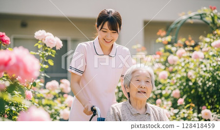 老年人與女性護理員一起在玫瑰園散步 老年人與女性護理員一起在玫瑰園散步作為休閒活動 128418459