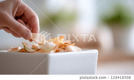 Hand places vegetable peelings into a clean compost bin, embracing urban gardening and sustainability 128418508