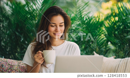 Young woman enjoying coffee while working on laptop in a lush tropical setting, embodying the essence of a digital nomad lifestyle 128418553