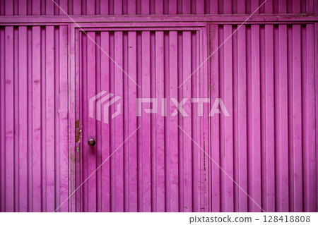 Painted pink and purple iron gates, fence for home front view. A closed door, doorway in bright fuchsia color. Security roller, shutter of garage. 128418808