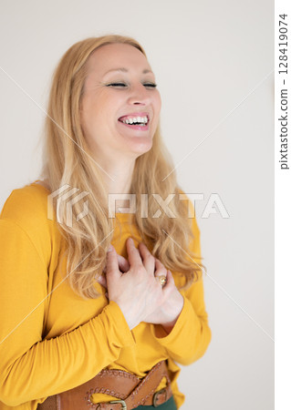 Portrait of cheerful confident beautiful woman with long blond hair, wearing casual clothes, standing in relaxed pose with hands on chest, breathing deeply, doing breathing exercise. Portrait of cheerful confident beautiful woman with long blond hair, wearing casual clothes, standing in relaxed pose with hands on chest, breathing deeply, doing breathing exercise. 128419074