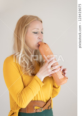 Portrait of female musician playing on traditional clay flute. Woman playing ocarina 128419075