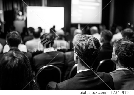 Speaker giving a talk in conference hall at business event. Rear view of unrecognizable people in audience at the conference hall. Business and entrepreneurship concept Speaker giving a talk in conference hall at business event. Rear view of unrecognizable people in audience at the conference hall. Business and entrepreneurship concept 128419101