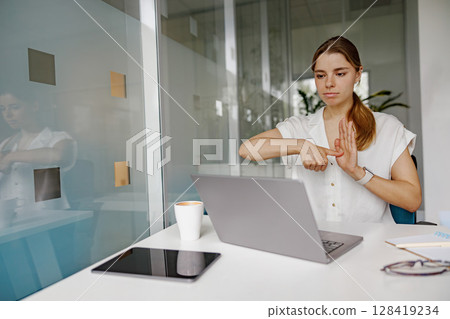 A woman is deeply engaged in virtual communication while working in a modern office setting 128419234