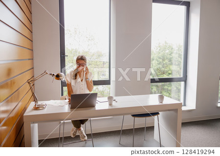 A Focused Young Woman Diligently Working at a Modern Desk in a Bright Office Space A Focused Young Woman Diligently Working at a Modern Desk in a Bright Office Space 128419294