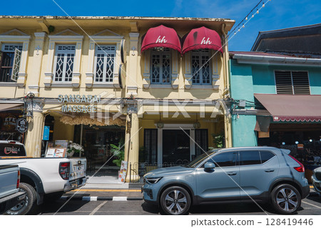 A yellow colonial style building with red awnings and Sansabai Massage on the ground floor, surrounded by parked vehicles and vibrant architecture. A yellow colonial style building with red awnings and Sansabai Massage on the ground floor, surrounded by parked vehicles and vibrant architecture. 128419446