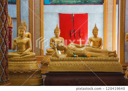 Serene temple interior in Thailand featuring a reclining Buddha statue, surrounded by seated Buddhas on ornate pedestals with vibrant red and gold decor. Serene temple interior in Thailand featuring a reclining Buddha statue, surrounded by seated Buddhas on ornate pedestals with vibrant red and gold decor. 128419648