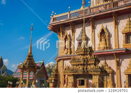 Ornate Wat Chalong temple in Phuket, Thailand, featuring golden details, pointed spires, and decorative carvings under a clear blue sky. Ornate Wat Chalong temple in Phuket, Thailand, featuring golden details, pointed spires, and decorative carvings under a clear blue sky. 128419701