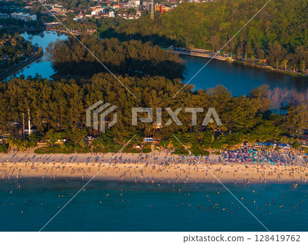 Aerial image of Naiharn Beach in Phuket, Thailand, featuring golden sand, dense greenery, a calm lagoon, and visitors enjoying the vibrant shoreline. Aerial image of Naiharn Beach in Phuket, Thailand, featuring golden sand, dense greenery, a calm lagoon, and visitors enjoying the vibrant shoreline. 128419762