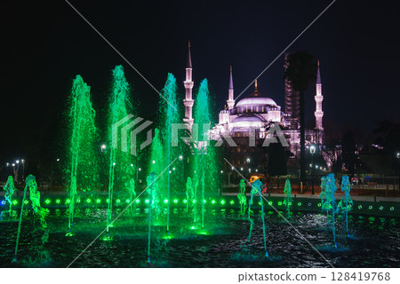The iconic Hagia Sophia in Istanbul, Turkey, glows at night with domes and minarets lit up, complemented by vibrant green lit fountains in the foreground. The iconic Hagia Sophia in Istanbul, Turkey, glows at night with domes and minarets lit up, complemented by vibrant green lit fountains in the foreground. 128419768