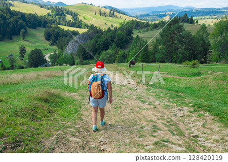 Senior Woman Walking on Forest Trail with Backpack 128420119