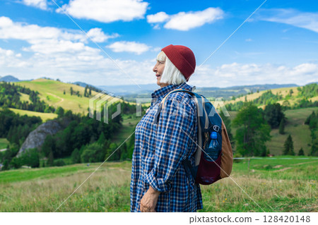 Senior woman enjoying scenic mountain landscape during hike 128420148