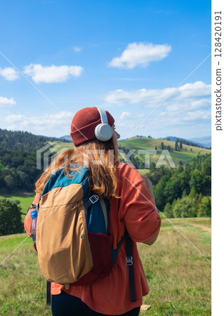 Woman Holding Headphones in Scenic Countryside 128420191