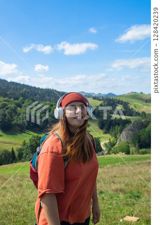 Woman Holding Headphones in Scenic Countryside 128420239