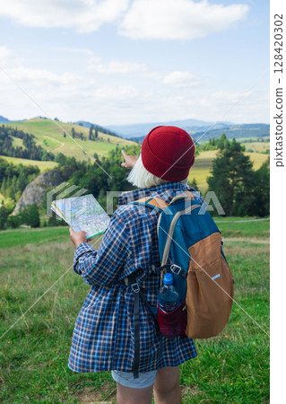 Female Hiker Navigating with a Map in the Mountains Female Hiker Navigating with a Map in the Mountains 128420302