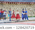 People wearing rental hanbok (traditional Korean dress) and official-style attire with Gyeongbokgung Palace in the background (generated by AI from original image) 128420719