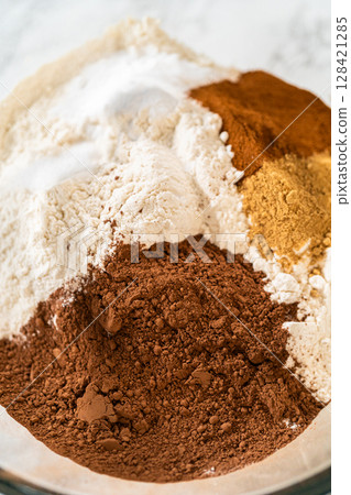 Close-up of a mixing bowl with cocoa powder, flour, ginger, and cinnamon for the Chocolate Ginger Sugar Cookie Dough, showing the spices and dry ingredients ready for mixing. Close-up of a mixing bowl with cocoa powder, flour, ginger, and cinnamon for the Chocolate Ginger Sugar Cookie Dough, showing the spices and dry ingredients ready for mixing. 128421285