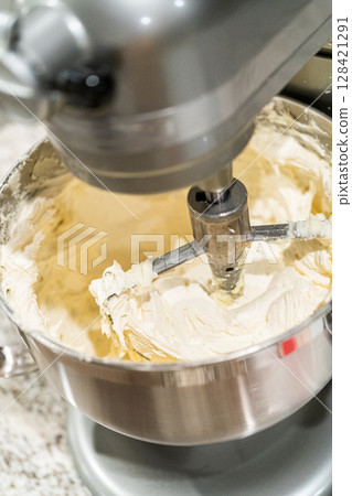 Stand mixer whips up creamy buttercream frosting to perfection, ready for dessert decorating. Stand mixer whips up creamy buttercream frosting to perfection, ready for dessert decorating. 128421291