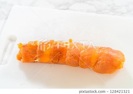 A fully rolled smoked salmon jumbo roll, showcasing the neat and compact structure of the appetizer. 128421321