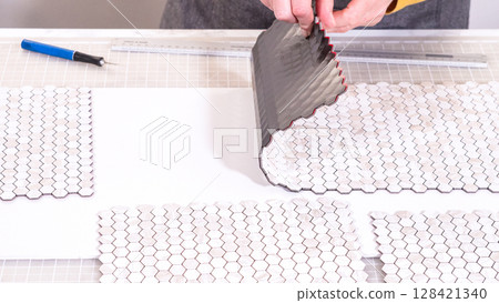 In the process of mounting peel and stick mosaic tiles onto a foam board, perfect for enhancing a food photography studio's aesthetic. In the process of mounting peel and stick mosaic tiles onto a foam board, perfect for enhancing a food photography studio's aesthetic. 128421340