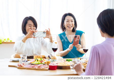 一名女子正在拍攝派對食物的照片 128421494